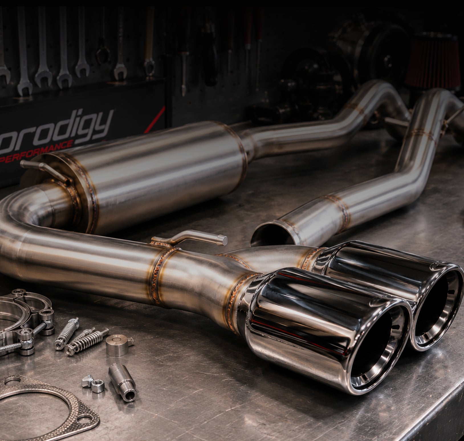 Metallic exhaust system on a workshop table with tools in the background