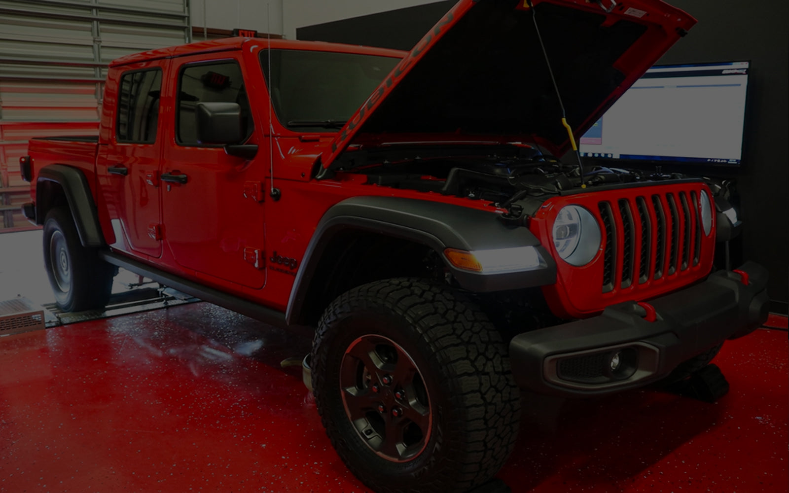 Red Jeep Wrangler with open hood in a garage setting