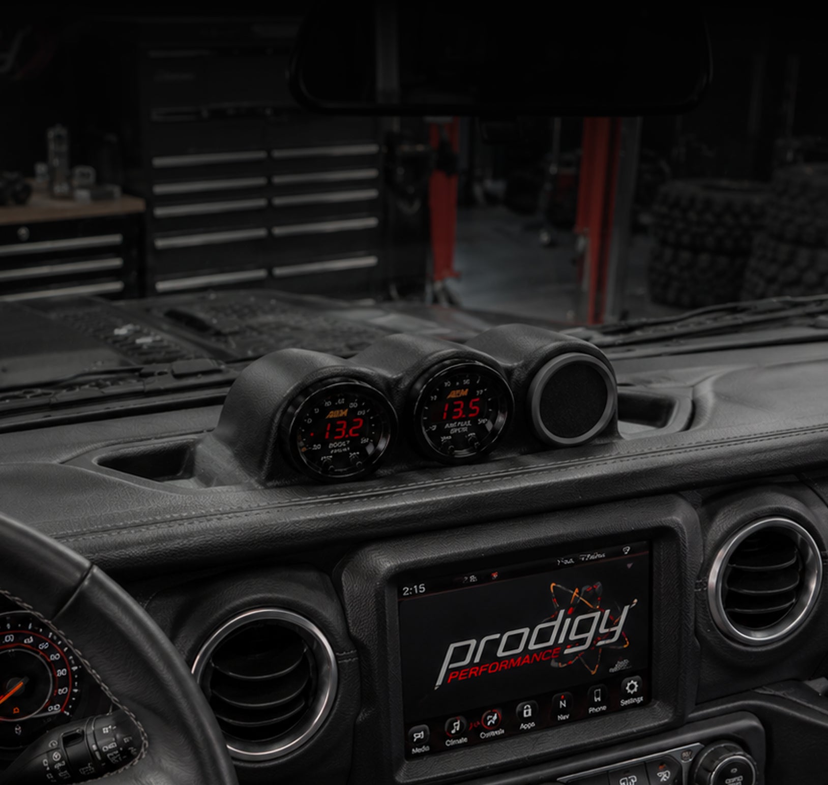 Car dashboard with Prodigy Performance gauges and display in a workshop setting
