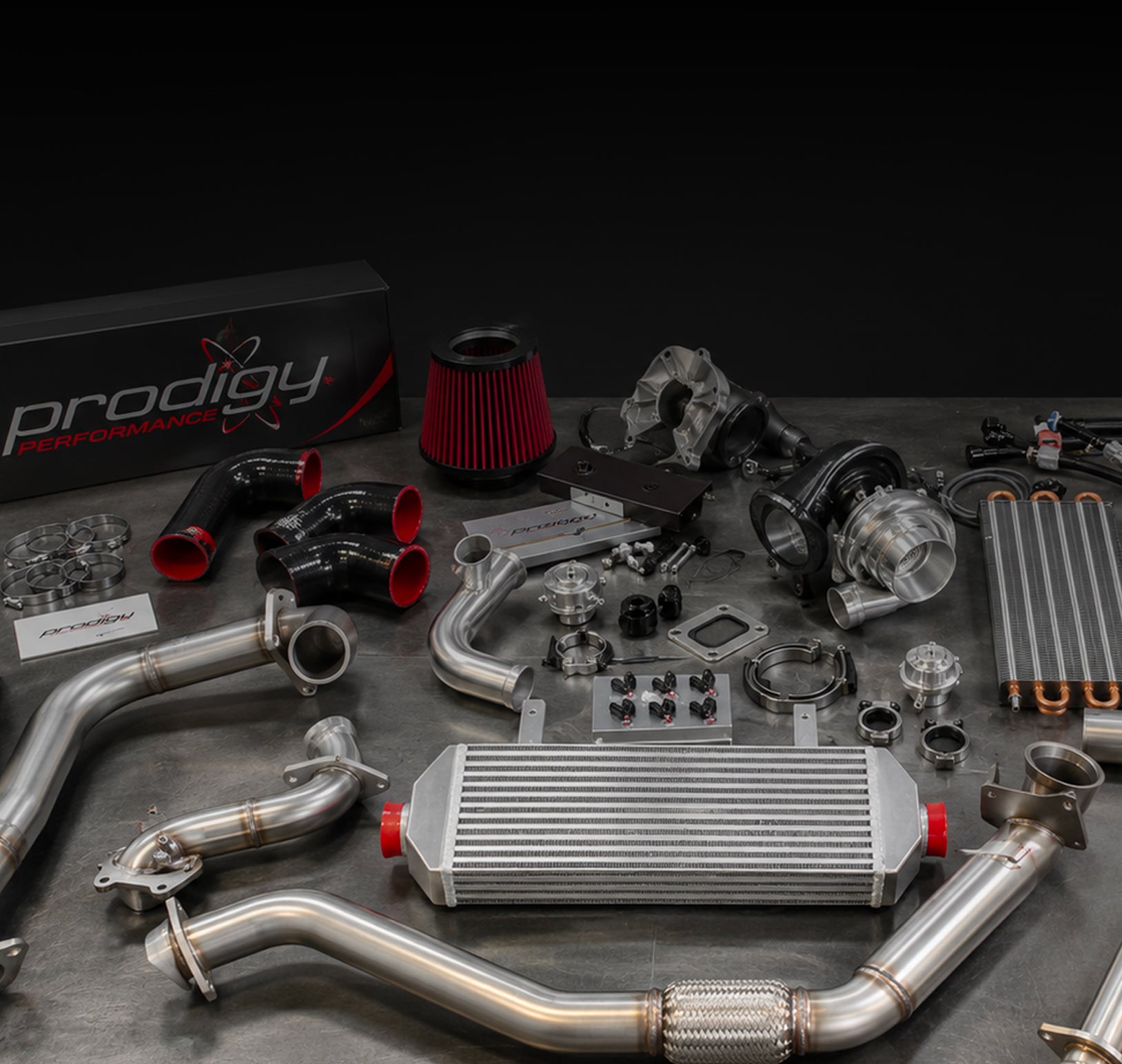 Collection of automotive parts on a dark surface with 'Prodigy Performance' branding.